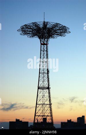 La nuova corsa in paracadute dormiente e inoperabile sul lungomare di Coney Island è resa in silhouette contro il cielo del tramonto a Brooklyn Foto Stock