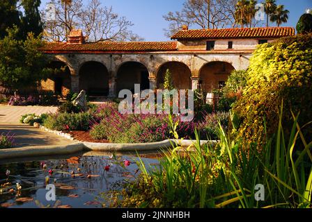 Il cortile della Missione San Juan Capistrano in California, mostra un bellissimo e colorato giardino piantato nella storica chiesa missionaria Foto Stock