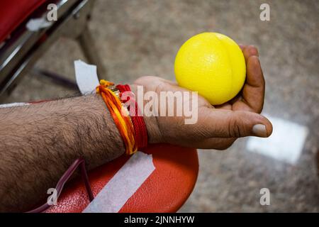 Donatore di sangue al campo di donazione di sangue tenuto con una palla rimbalzante in mano al Tempio Balaji, Vivek Vihar, Delhi, India, Image for World Blood Donor da Foto Stock