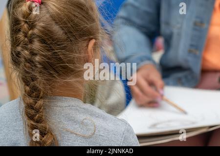 una vista posteriore dei capelli con un pigtail intrecciato di una bambina, un bambino Foto Stock