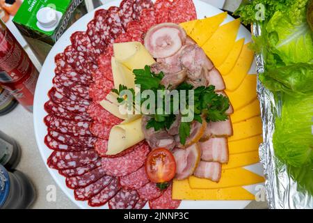 Un piatto di antipasti freddi con varie salsicce, carne e formaggio. Verdi e pomodori. Foto Stock