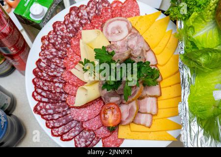 Un piatto di antipasti freddi con varie salsicce, carne e formaggio. Verdi e pomodori. Foto Stock