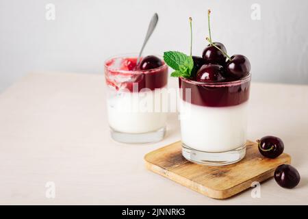 Dessert di gelatina. Yogurt e gelatina di ciliegia su sfondo chiaro. Foto Stock