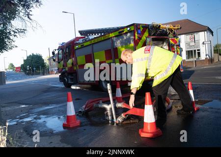 Slough, Berkshire, Regno Unito. 13th agosto, 2022. Un motore antincendio aspira l'acqua da un idrante. Il Royal Berkshire Fire and Rescue Service stavate mettendo fuori un fuoco presso lo stabilimento di riciclaggio Simpson a Simpsons Way, Slough questa mattina dietro il Tempio di Ramgarhia Sikh. Ai residenti è stato consigliato di rimanere all'interno e tenere le finestre chiuse. Un camion Zetros che contiene 8.000 litri d'acqua è stato anche sulla scena per smorzare il fuoco. Credit: Maureen McLean/Alamy Live News Foto Stock