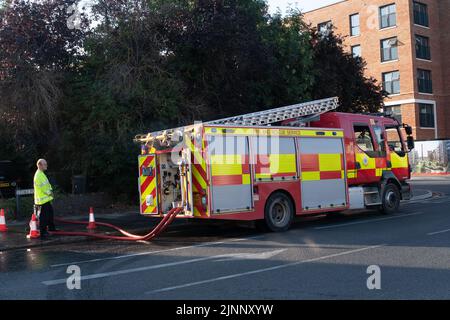 Slough, Berkshire, Regno Unito. 13th agosto, 2022. Un motore antincendio aspira l'acqua da un idrante. Il Royal Berkshire Fire and Rescue Service stavate mettendo fuori un fuoco presso lo stabilimento di riciclaggio Simpson a Simpsons Way, Slough questa mattina dietro il Tempio di Ramgarhia Sikh. Ai residenti è stato consigliato di rimanere all'interno e tenere le finestre chiuse. Un camion Zetros che contiene 8.000 litri d'acqua è stato anche sulla scena per smorzare il fuoco. Credit: Maureen McLean/Alamy Live News Foto Stock