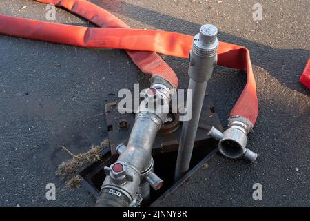 Slough, Berkshire, Regno Unito. 13th agosto, 2022. Un motore antincendio aspira l'acqua da un idrante. Il Royal Berkshire Fire and Rescue Service stavate mettendo fuori un fuoco presso lo stabilimento di riciclaggio Simpson a Simpsons Way, Slough questa mattina dietro il Tempio di Ramgarhia Sikh. Ai residenti è stato consigliato di rimanere all'interno e tenere le finestre chiuse. Un camion Zetros che contiene 8.000 litri d'acqua è stato anche sulla scena per smorzare il fuoco. Credit: Maureen McLean/Alamy Live News Foto Stock