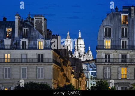 Parigi (75) Immeubles de style haussmannien sur la rue Rivoli, avec en arriere-plan, au crepuscule, la basilique du Sacre-Cœur a Montmartre Foto Stock