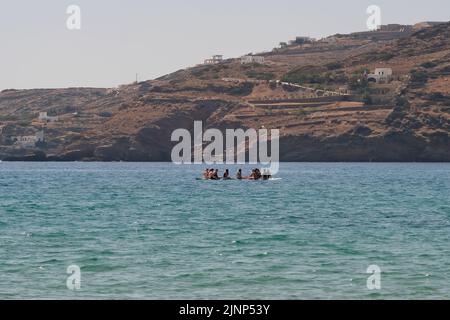 IOS, Grecia - 8 giugno 2021 : i giovani turisti con tavole di pagaia standup hanno formato un cerchio per parlare e riposare sulla spiaggia di Mylopotas in Grecia iOS Foto Stock