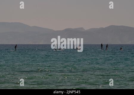 IOS, Grecia - 8 giugno 2021 : i giovani turisti che si divertiscono con il paddle boarding sulla famosa spiaggia di Mylopotas iOS Greece Foto Stock