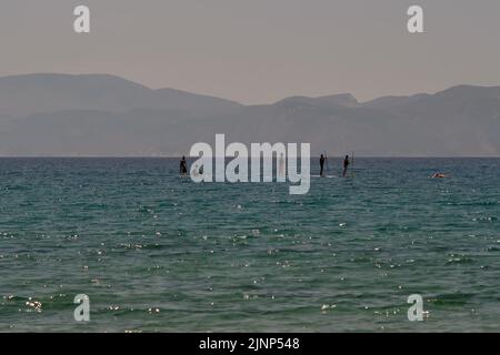 IOS, Grecia - 8 giugno 2021 : i giovani turisti che si divertiscono con il paddle boarding sulla famosa spiaggia di Mylopotas iOS Greece Foto Stock