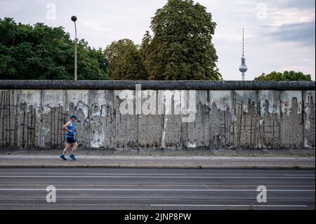 Berlino, Germania. 13th ago, 2022. Un pareggiatore passa davanti al Memoriale del Muro di Berlino la mattina presto. Credit: Fabian Sommer/dpa/Alamy Live News Foto Stock