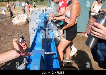 SOLO PER USO EDITORIALE i festaioli cercano di rimanere freschi durante un'ondata di caldo alla fiera Boomtown di quest'anno, sulla tenuta di Matterley, Ovington, Hampshire. Data foto: Sabato 13 agosto 2022. L'evento, a cui partecipano 66.000 persone quest'anno, è uno dei più grandi festival musicali e teatrali del Regno Unito. Il credito fotografico dovrebbe essere: Craig Gunn/PA Wire Foto Stock