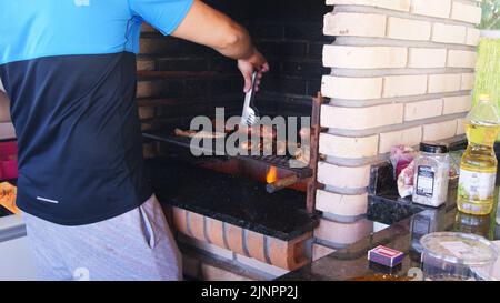 Giovane arrosto di carne e salsiccia su griglia barbecue con coltello e forchetta con denti, Brasile, Sud America, zoom foto Foto Stock