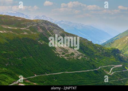 Pittoresco paesaggio estivo. Passo Furka nelle Alpi Svizzere. La strada a serpentina passa attraverso le montagne ricoperte di fitta vegetazione. Foto Stock