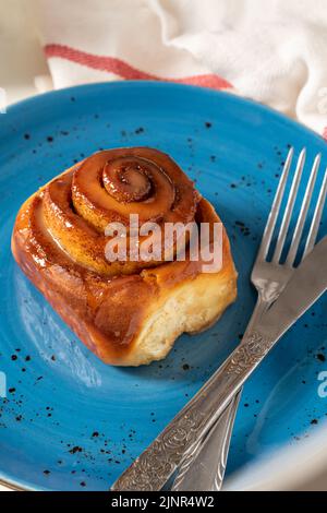 Rotolo di cannella appena sfornato su un piatto di porcellana blu Foto Stock