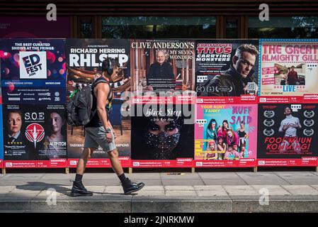 Un giovane che cammina per i poster del Festival della fringe di Edimburgo a George Square, Edimburgo, Scozia, Regno Unito. Foto Stock