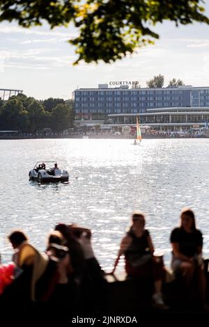 Hannover, Germania. 13th ago, 2022. La gente si sofferma al Maschseefest sulla riva di Rudolf-von-Bennigsen sul lago Maschsee. Il Maschseefest 35th si svolge ad Hannover dal 27 luglio al 14 agosto. Credit: Michael Matthey/dpa/Alamy Live News Foto Stock