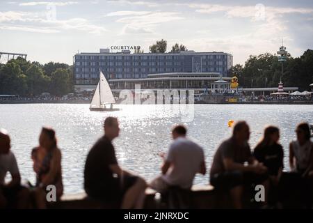 Hannover, Germania. 13th ago, 2022. La gente si sofferma al Maschseefest sulla riva di Rudolf-von-Bennigsen sul lago Maschsee. Il Maschseefest 35th si svolge ad Hannover dal 27 luglio al 14 agosto. Credit: Michael Matthey/dpa/Alamy Live News Foto Stock