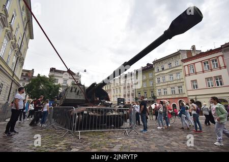 La gente guarda un impianto di artiglieria semovente russa in una mostra di attrezzature russe distrutte a Lviv. Organizzata dal governo ucraino, questa mostra sarà nel centro di Lviv fino alla fine dell'estate. Poi sarà trasferito nei paesi del Nord America. L'idea è quella di esporre i crimini che gli occupanti russi hanno commesso sul territorio ucraino. Foto Stock