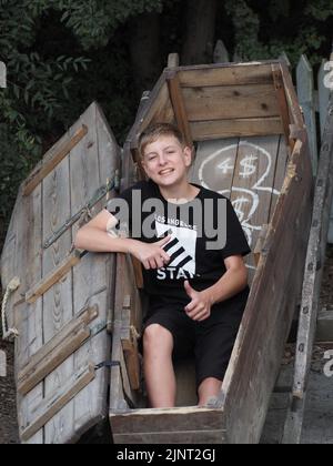 Sorridente adolescente si pone per una foto in una bara di legno a Pullman City Foto Stock