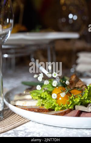 carne affettata con erbe e pomodori su un primo piano piatto bianco. Foto Stock