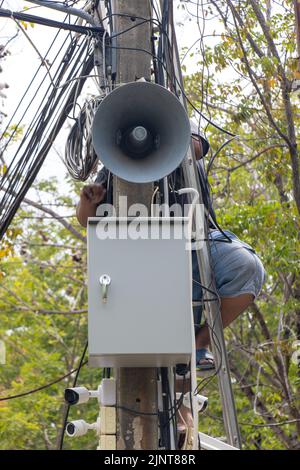 Un uomo esegue la manutenzione su un palo con un megafono Foto Stock