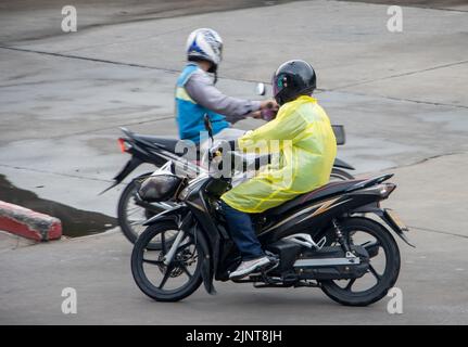 I tassisti moto si guidano su una strada bagnata, Thailandia Foto Stock