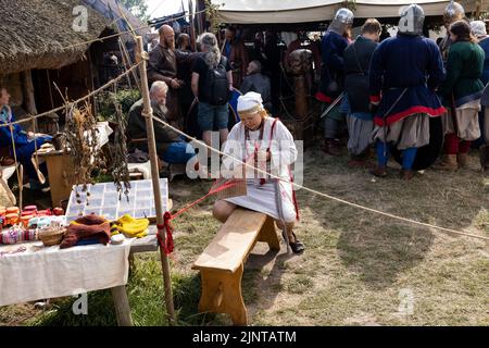 WOLIN, POLONIA - 6 AGOSTO 2022: XXVII Festival degli Slavi e dei Vichinghi, donna che tesse una tradizionale cintura medievale di stoffa (krajka) Foto Stock