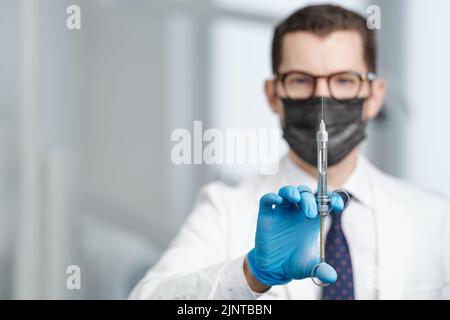 Colpo di primo piano della siringa nelle mani di un medico di sesso maschile Foto Stock