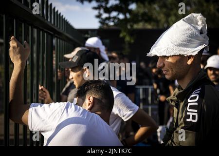 2022-08-13 18:22:19:19 ter APEL - i richiedenti asilo aspettano al recinto per essere detto se dovrebbero dormire fuori della notte successiva o meno. Le conseguenze dell'interruzione del traffico di richiedenti asilo sono state più intense da mesi nel centro di applicazione di Groningen. E 'stato sovraffollata per un po 'di tempo, quindi le persone devono regolarmente dormire fuori. ANP RAMON VAN FLYMEN olanda fuori - belgio fuori Foto Stock