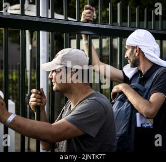 2022-08-13 18:25:36:19 ter APEL - i richiedenti asilo aspettano al recinto per essere detto se dovrebbero dormire fuori della notte successiva o meno. Le conseguenze dell'interruzione del traffico di richiedenti asilo sono state più intense da mesi nel centro di applicazione di Groningen. E 'stato sovraffollata per un po 'di tempo, quindi le persone devono regolarmente dormire fuori. ANP RAMON VAN FLYMEN olanda fuori - belgio fuori Foto Stock