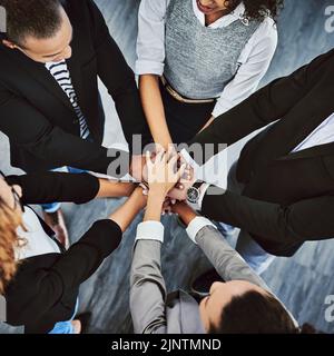 L'unica strada da percorrere è quella dell'Unione. Colpo ad angolo alto di un gruppo di uomini d'affari che uniscono le loro mani in una huddle. Foto Stock