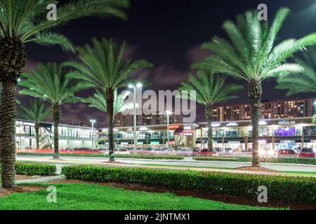 Sunny Isles Beach, FL, USA - 1 agosto 2022: Foto notturna dei negozi del RK Center e delle palme che ondeggiano nel vento Foto Stock