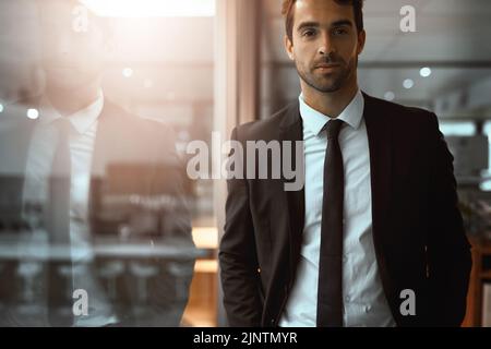 In piedi alto nel suo impero di successo. Ritratto di un giovane uomo d'affari in un ufficio. Foto Stock