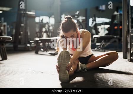 Allunga oltre i tuoi limiti. Una giovane donna che fa esercizi di stretch in palestra. Foto Stock