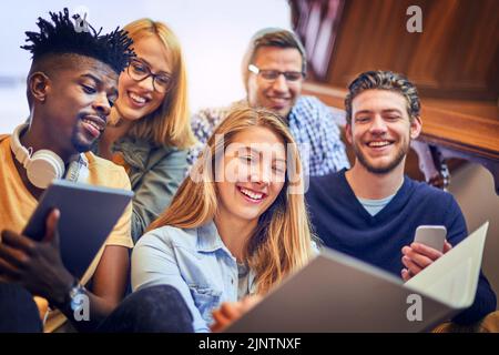 Andiamo oltre questa volta ancora. Un gruppo di studenti universitari diversi che lavorano insieme sulla scala del campus. Foto Stock