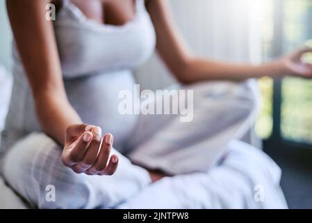 Lo yoga prenatale può essere la cura per ciò che vi affligge. Una donna incinta che fa yoga nella sua camera da letto. Foto Stock