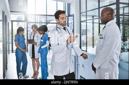 Dobbiamo costruire un gruppo per questa procedura: Due medici che discutano in un ospedale. Foto Stock