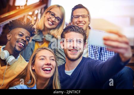Amici nel campus, amici per sempre. Un gruppo di studenti universitari diversi che prendono un selfie sulla scala del campus. Foto Stock