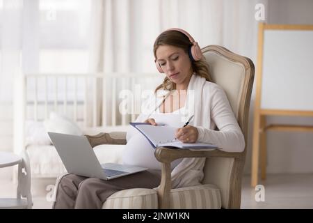 Donna incinta uso laptop ottenere consultazione online, scrive informazioni utili Foto Stock