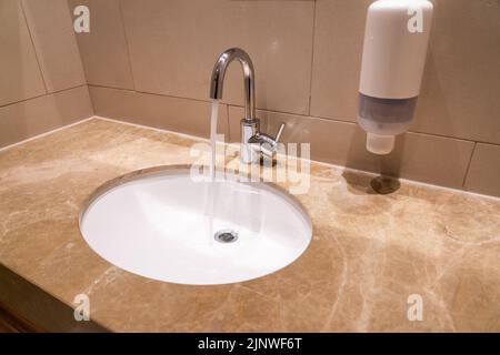 Lavandino con rubinetto in un bagno d'hotel su una base di granito Foto Stock