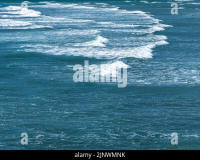 Bellissima schiuma sulle onde maree turchesi. La superficie dell'acqua come sfondo. Acqua blu dell'oceano Foto Stock