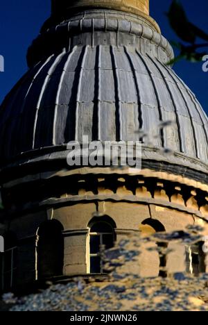 Una leggera brezza ruba la superficie del lago prima dell'ex Bliss Tweed Mill a Chipping Norton, Oxfordshire, Inghilterra, Regno Unito, offuscando le linee della sua torre dell'orologio circolare, ricoperta da una caratteristica cupola rivestita in piombo e da un'elegante ciminiera. Il mulino è stato chiuso nel 1980 ma ora è diviso in appartamenti di lusso. Foto Stock