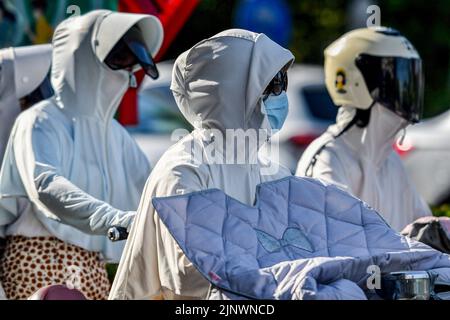 Fuyang, Cina. 14th ago, 2022. Le donne hanno visto andare in bicicletta elettrica sulla strada mentre indossano suite con crema solare, maschere e occhiali da sole verso i forti raggi ultravioletti. L'Osservatorio Meteorologico Centrale della Cina ha emesso un avvertimento rosso ad alta temperatura. Si prevede che la temperatura massima in alcune parti della Cina raggiungerà oltre i 40 ? Il 14 agosto. Credit: SOPA Images Limited/Alamy Live News Foto Stock