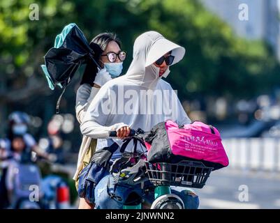 Fuyang, Cina. 14th ago, 2022. Una donna ha visto guidare una bicicletta elettrica sulla strada mentre indossa un costume da protezione solare e occhiali da sole verso i forti raggi ultravioletti. L'Osservatorio Meteorologico Centrale della Cina ha emesso un avvertimento rosso ad alta temperatura. Si prevede che la temperatura massima in alcune parti della Cina raggiungerà oltre i 40 ? Il 14 agosto. (Foto di Sheldon Cooper/SOPA Images/Sipa USA) Credit: Sipa USA/Alamy Live News Foto Stock