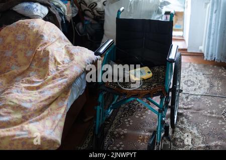 sedia a rotelle vuota in una vecchia casa molto povera Foto Stock