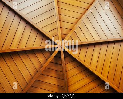 Fondo di costruzione in legno, disposto a forma rotonda, sotto il tetto. Struttura interna di un soffitto a doga di legno a cupola, disegno circolare, ragnatela Foto Stock