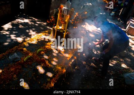 Una donna messicana, che tiene un bruciatore di incenso fumante, esegue una purificazione di una tomba durante le celebrazioni del giorno dei morti a Tlapa de Comonfort, Messico. Foto Stock