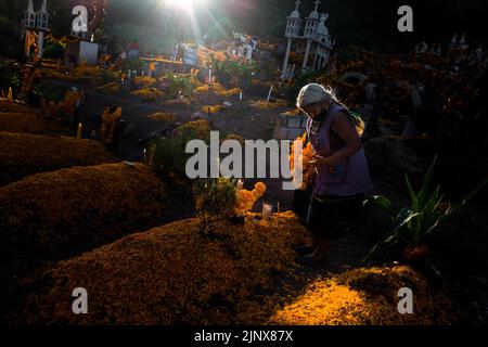 Una donna indigena Mixtec decora una tomba in un cimitero durante le celebrazioni del giorno dei morti a Xalpatláhuac, Guerrero, Messico. Foto Stock