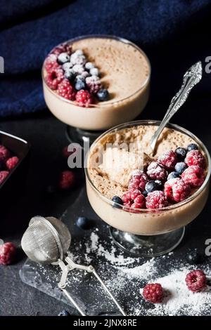 Mousse Ryazhenka (latte fermentato al forno) in ciotole di vetro decorate con frutti di bosco freschi Foto Stock